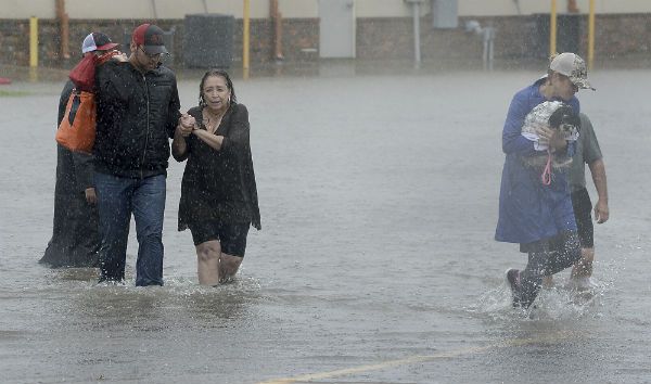 德州亚瑟港30日降雨盈呎，充作灾民收容中心的包尔斯市民中心也遭水患，受困的灾民只能坐在看台上。(美联社)