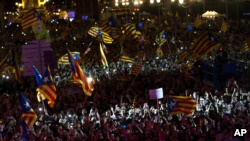 人们在西班牙巴塞罗那街头游行，手中挥舞着加泰罗尼亚旗帜