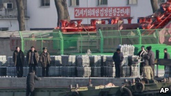 朝鲜公民在朝鲜新义州河岸的船上卸货。新义州对面就是中国与朝鲜的边境城市丹东。(资料照。摄于2011年12月30日。)
