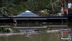 在波多黎各的瓜亚塔卡水坝附近，洪水淹没房屋，人们站在房顶上（2017年9月23日）