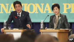 日本自民党党魁和首相安倍晋三(左) 10月8日在政党领袖辩论会中发表讲话。希望之党的领袖小池百合子在一旁聆听。